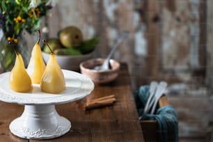 a white plate topped with two pears on top of a wooden table