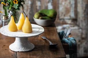 three pears on a white plate on a wooden table