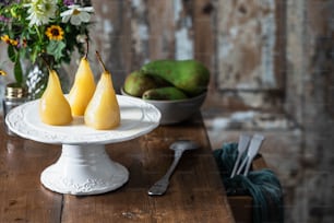 três peras sentadas em um prato branco sobre uma mesa