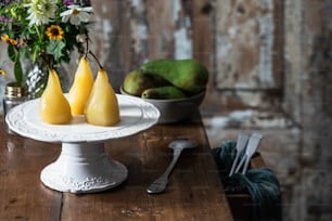 três peras em um prato branco em uma mesa de madeira
