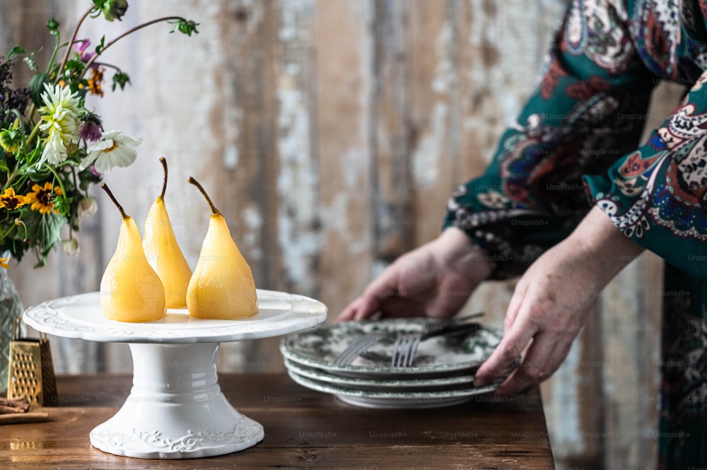 a woman is cutting pears on a cake plate