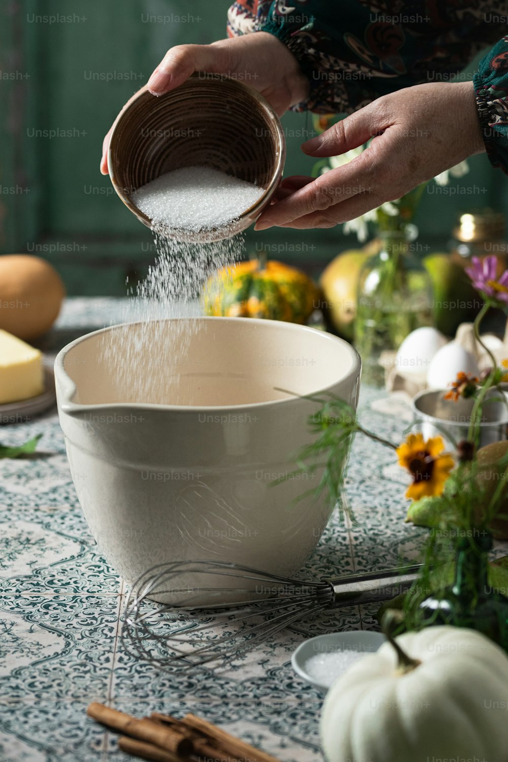 a person pouring sugar into a bowl on a table
