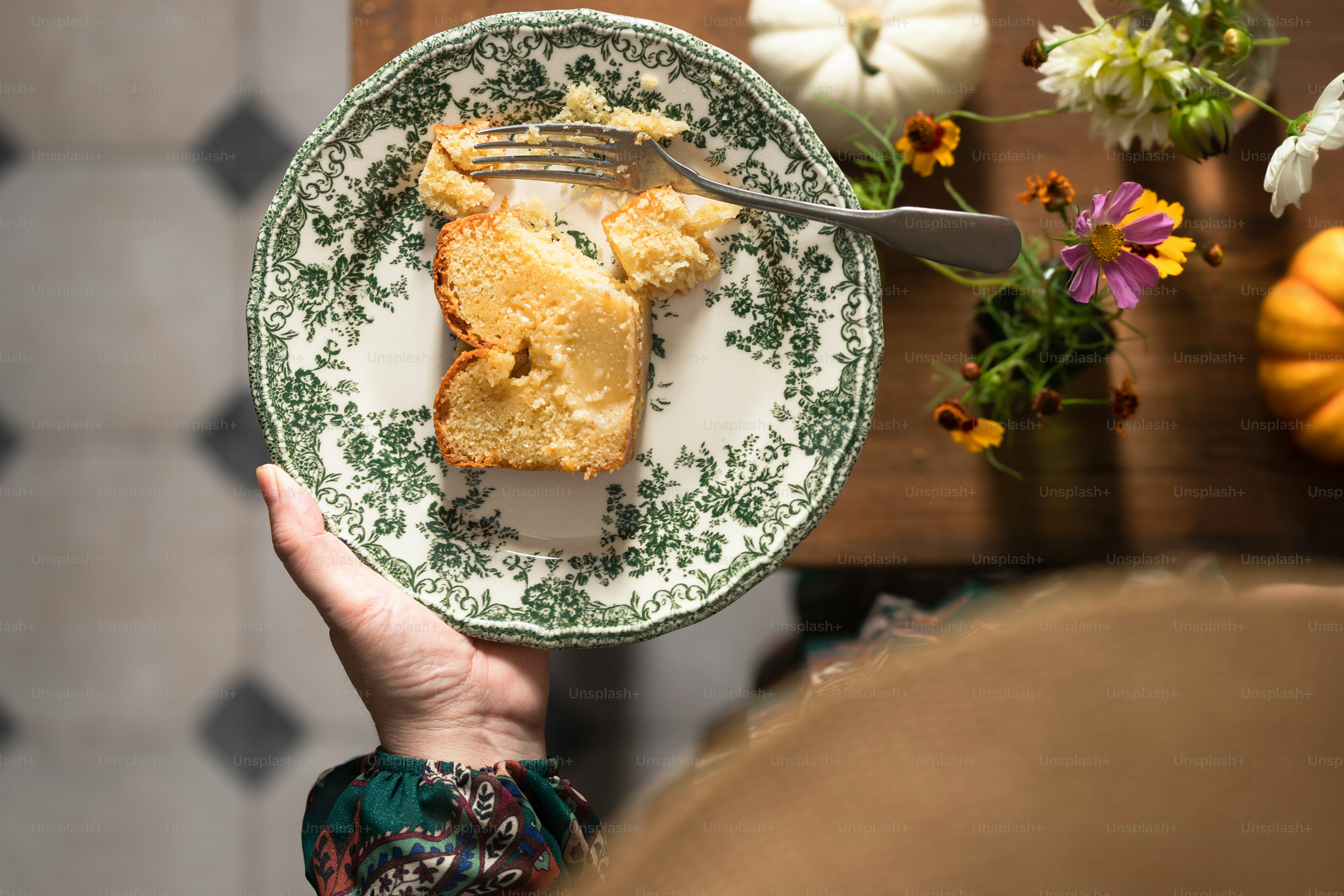 a person holding a plate with a piece of cake on it