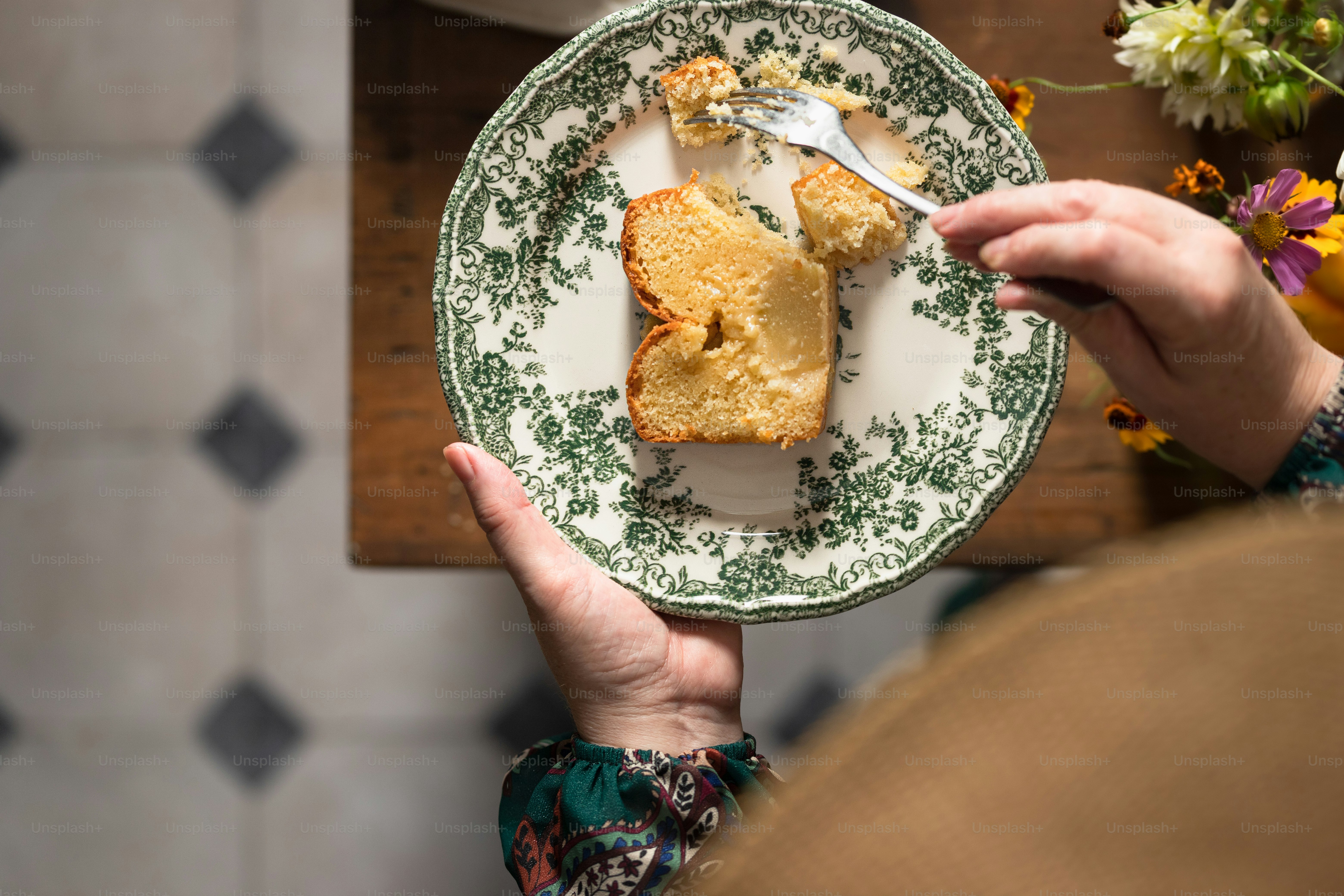 a person holding a plate with a piece of cake on it