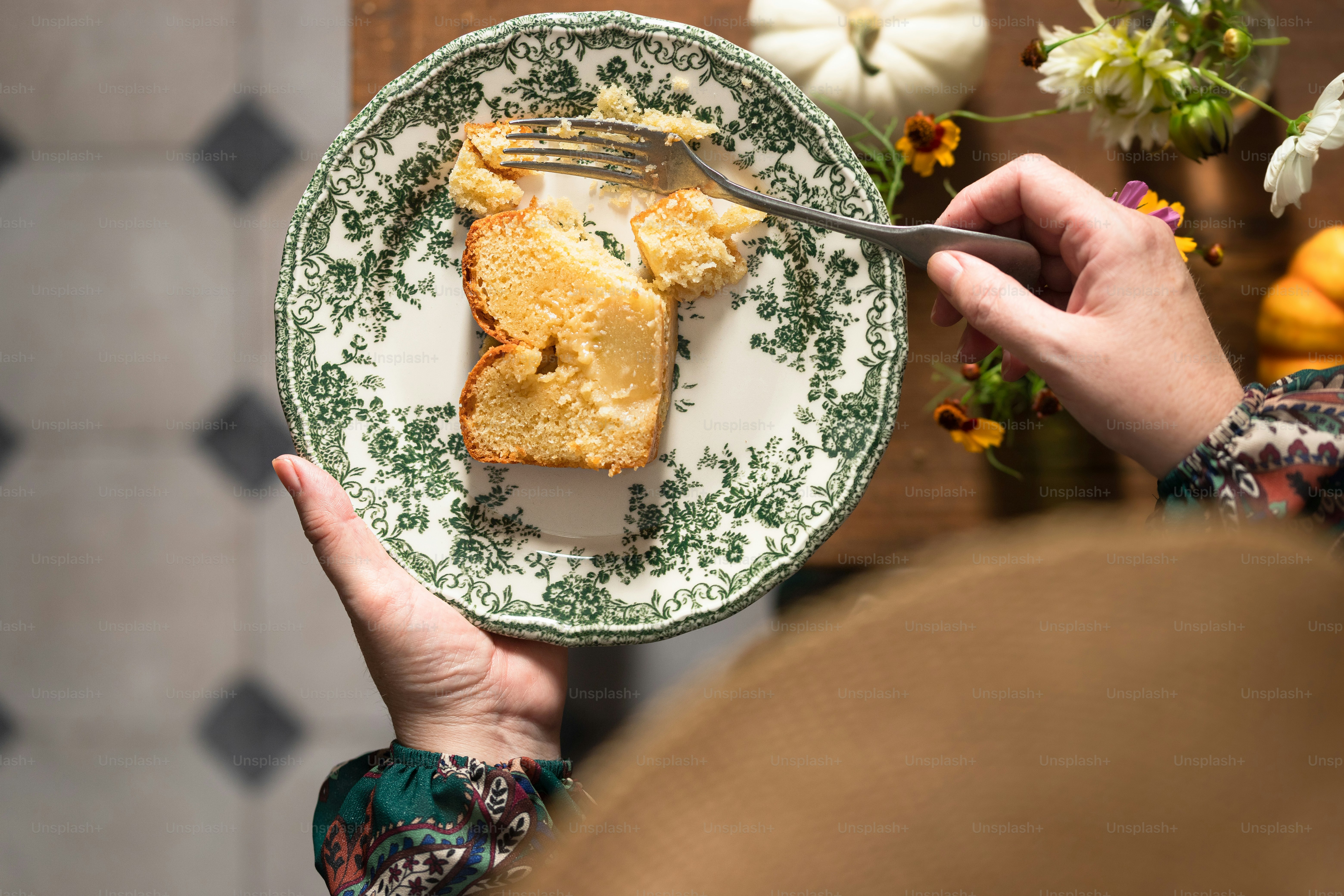 a person holding a plate with a piece of cake on it
