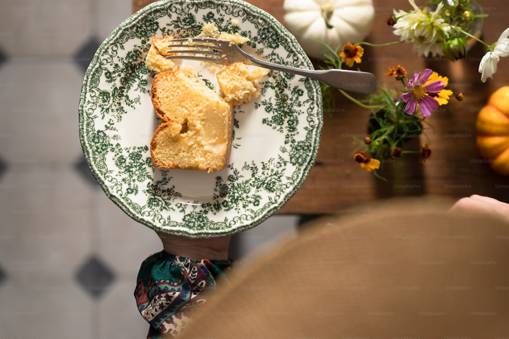 a person holding a plate with a piece of cake on it