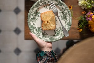 a person holding a plate with a piece of cake on it