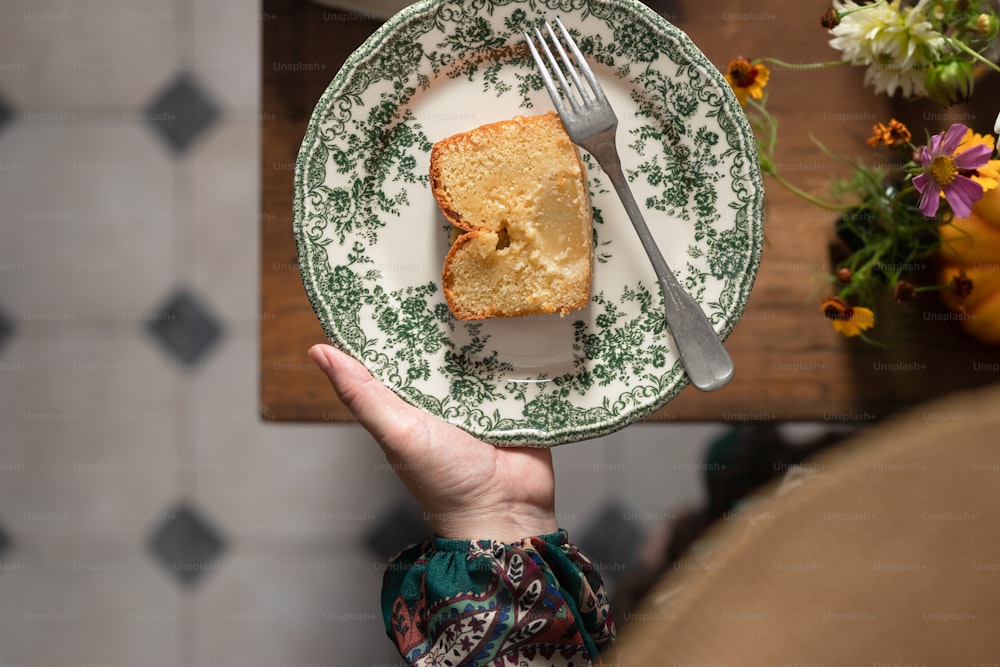 a person holding a plate with a piece of cake on it