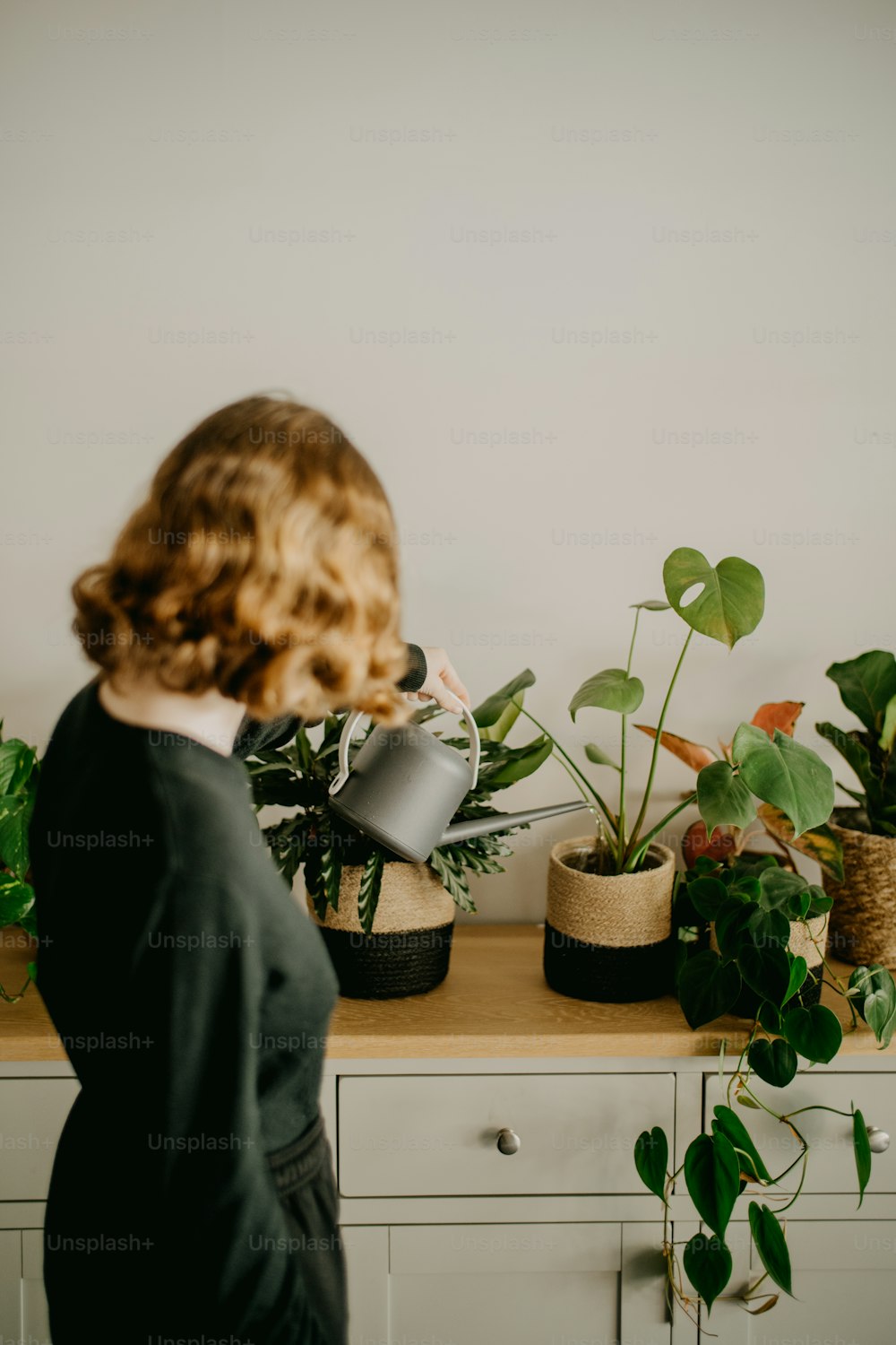 a woman standing in front of a table with potted plants