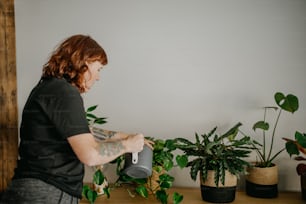 a woman standing in front of a table filled with potted plants