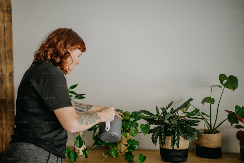 Una mujer parada frente a una mesa llena de plantas en macetas