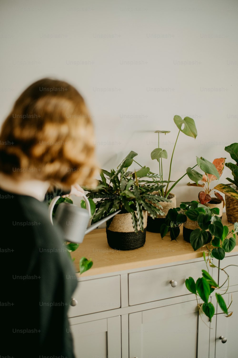 a woman is looking at plants on a dresser