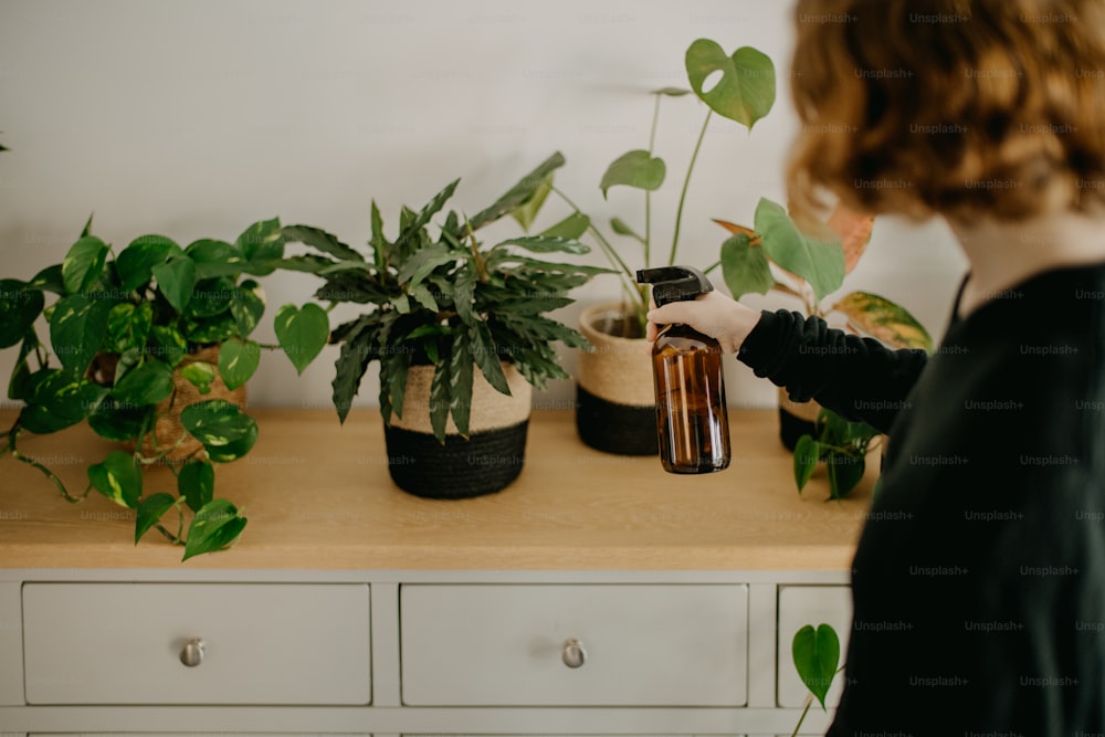 uma mulher em pé em frente a uma mesa cheia de vasos de plantas