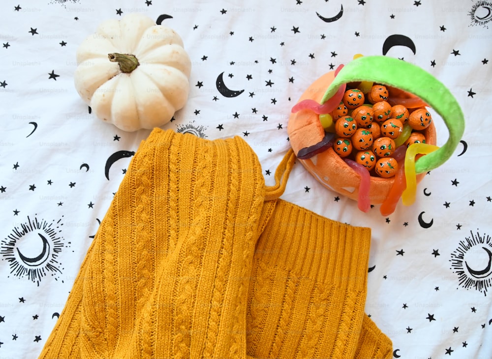 a yellow sweater and pumpkins on a bed