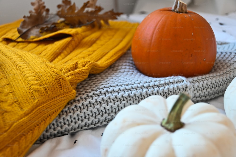 a white pumpkin sitting on top of a bed next to a yellow sweater