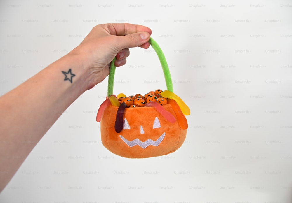 a hand holding a small pumpkin shaped bag