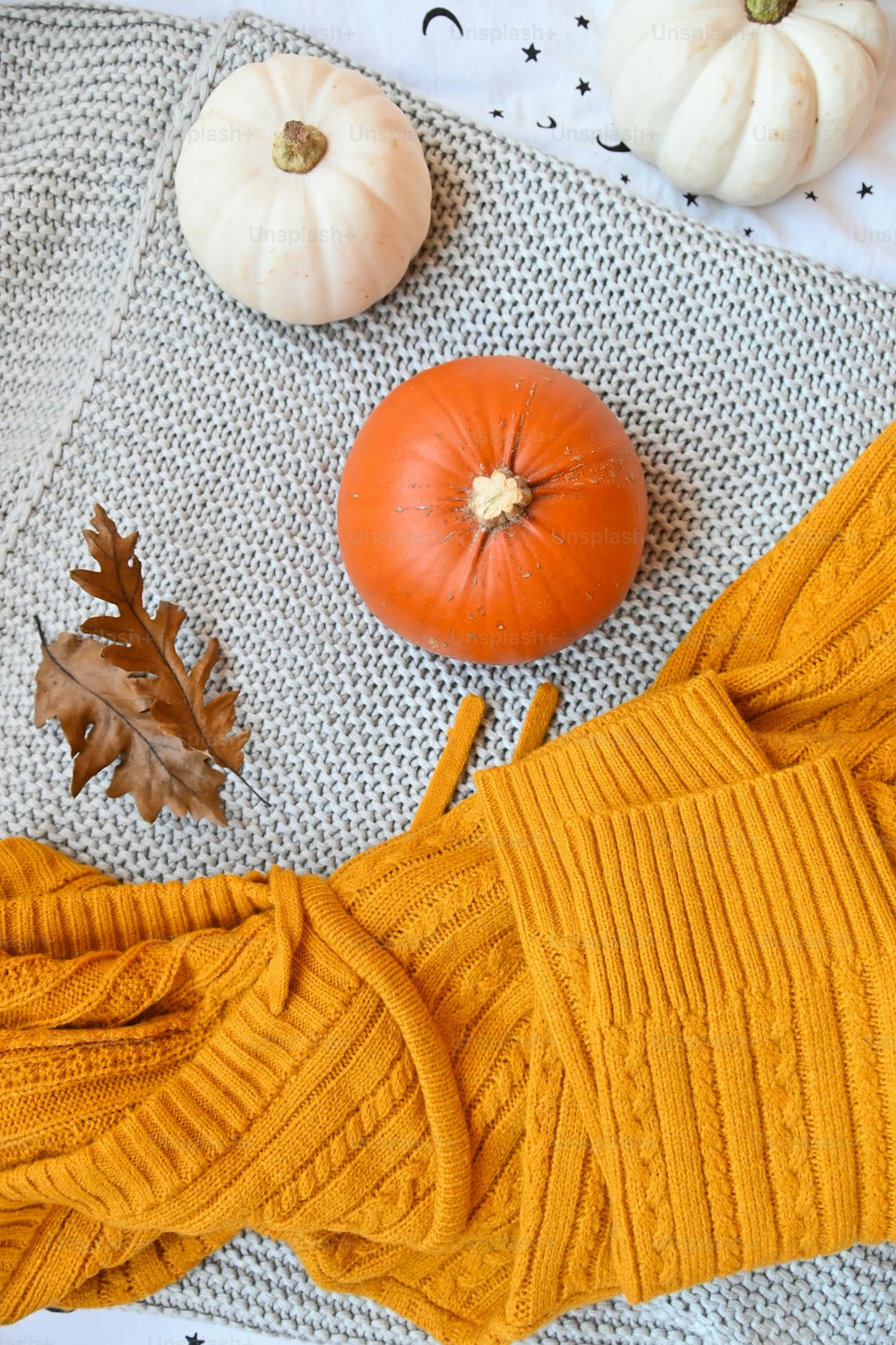 un pull jaune et des citrouilles sur une couverture