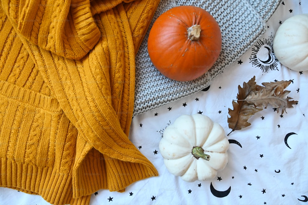 a blanket, pumpkins, and leaves on a bed