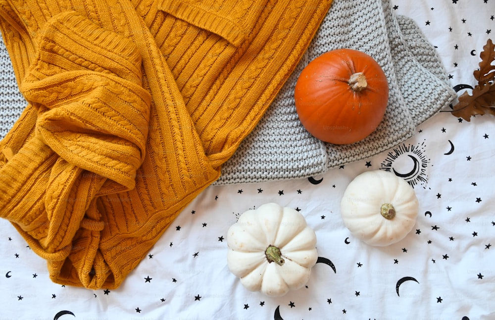 pumpkins and a yellow sweater on a bed