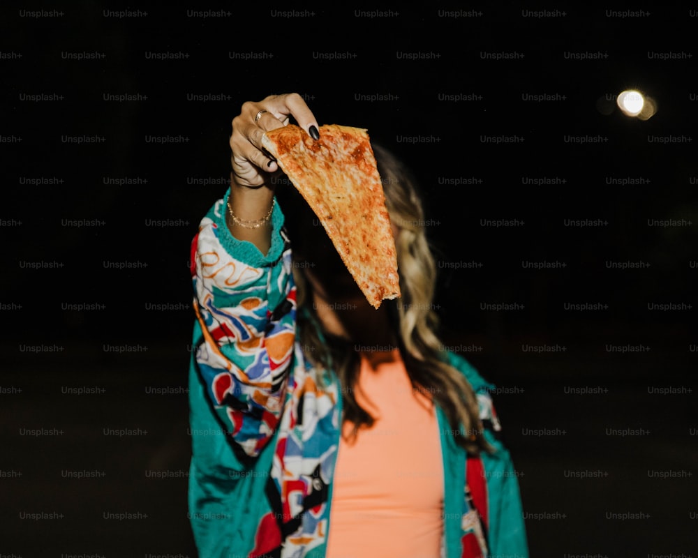 Una mujer sosteniendo una rebanada de pizza en su cara