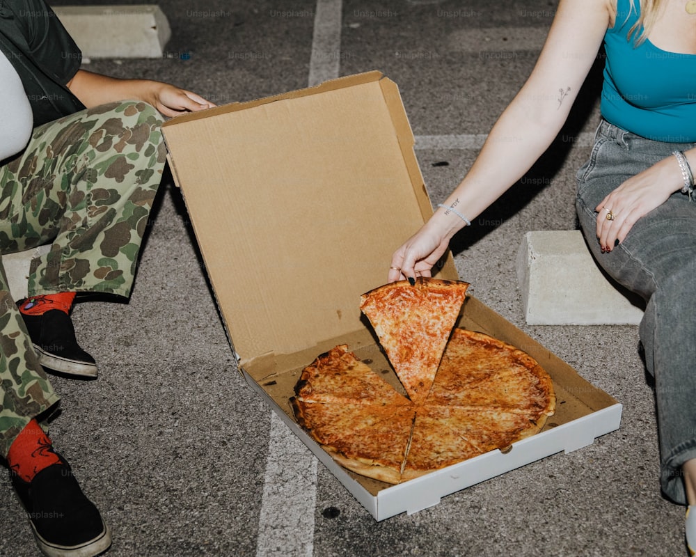 Una mujer está tomando una rebanada de pizza de una caja