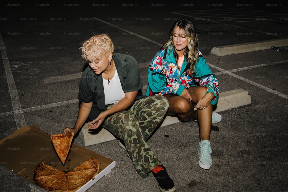 地面に座ってピザを食べる男女
