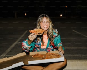 Une femme assise par terre mangeant une part de pizza