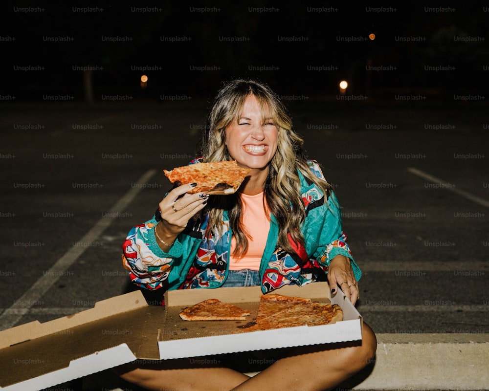 a woman sitting on the ground eating a slice of pizza