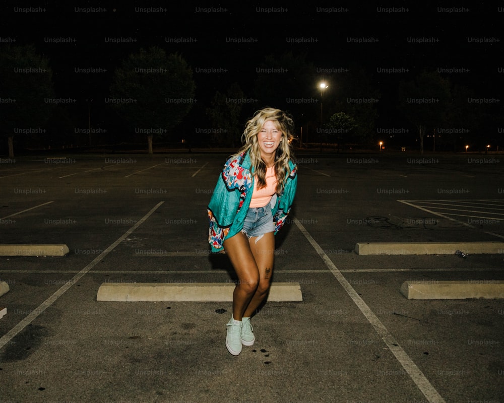 a woman standing in a parking lot at night