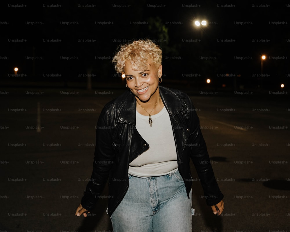 a woman in jeans and a leather jacket smiles at the camera