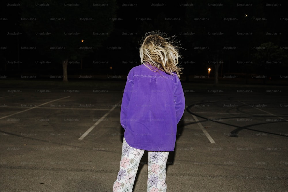 Una mujer parada en un estacionamiento por la noche