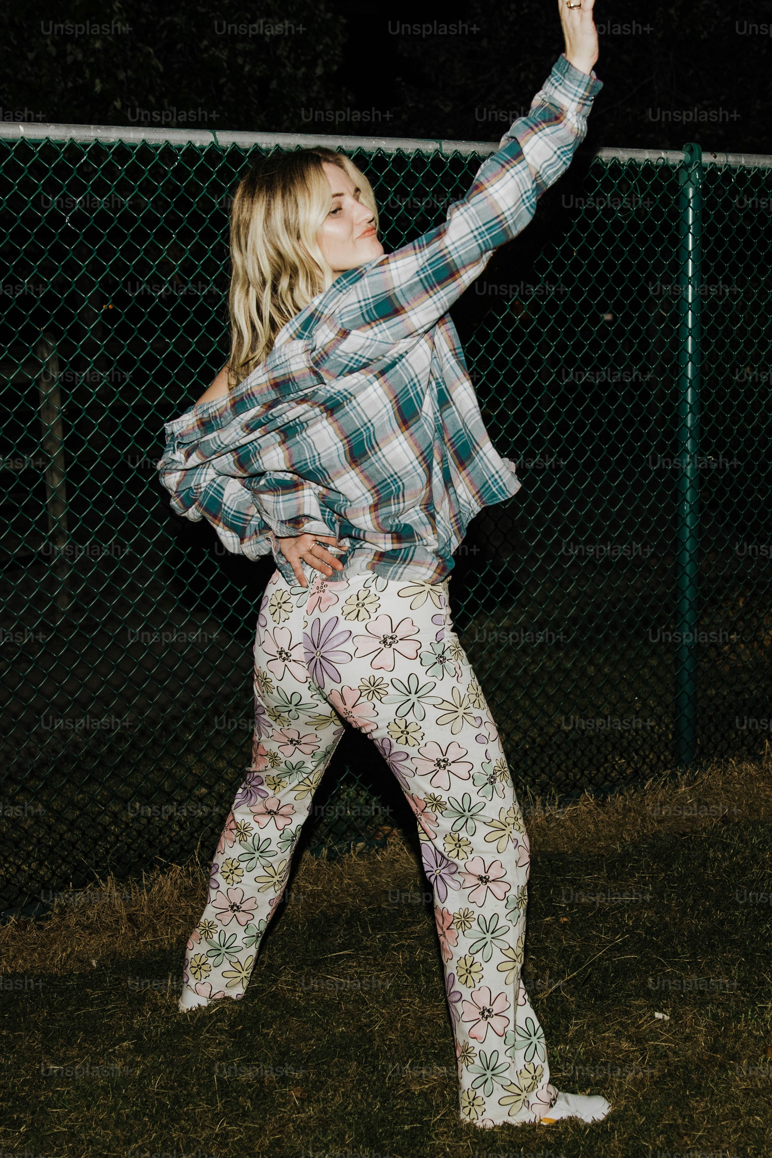 a woman standing in front of a fence holding a frisbee