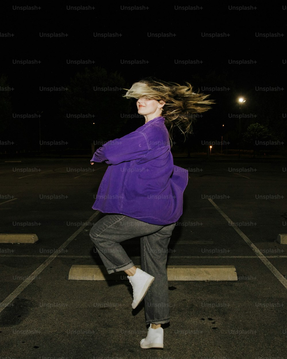 a woman in a parking lot with her hair in the air