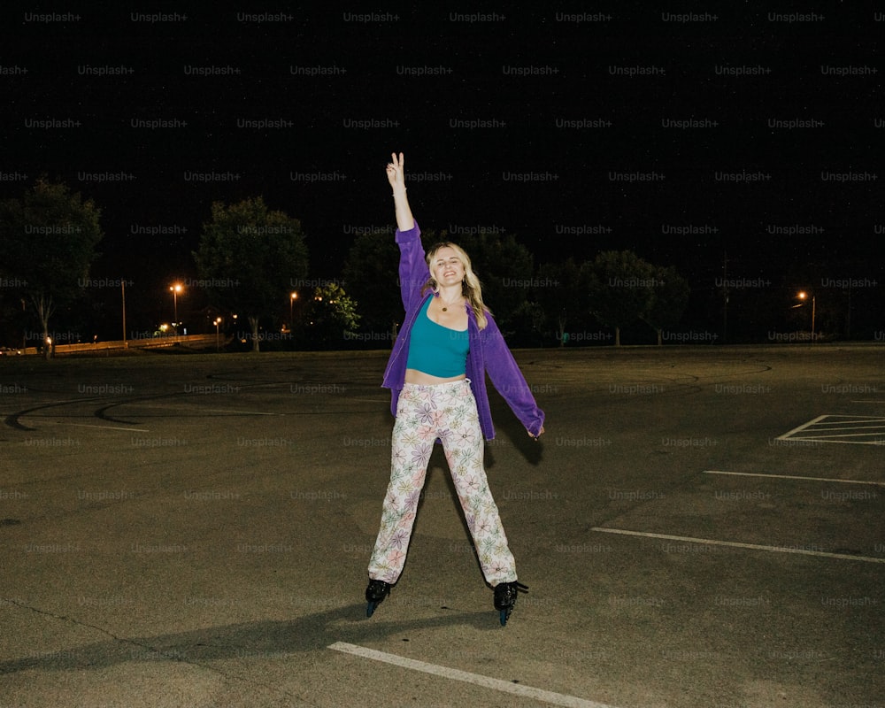 a woman standing in a parking lot with her arms in the air