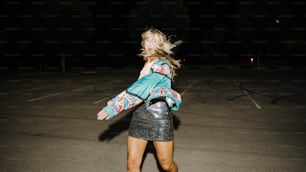 a woman walking across a parking lot at night