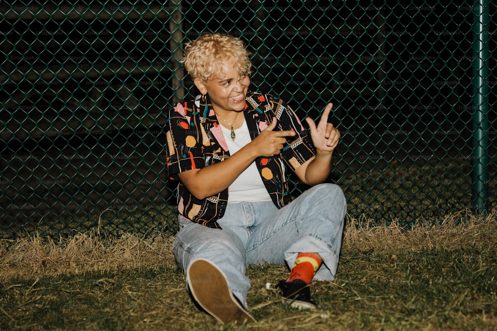 a person sitting in the grass making a peace sign