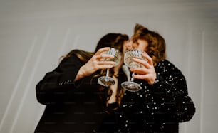 a couple of women standing next to each other holding wine glasses