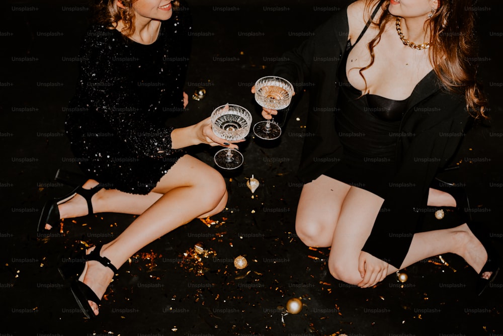 a couple of women sitting next to each other holding wine glasses