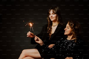 a couple of women sitting next to each other holding sparklers