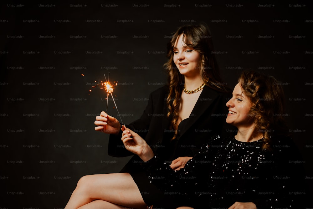 a couple of women sitting next to each other holding sparklers