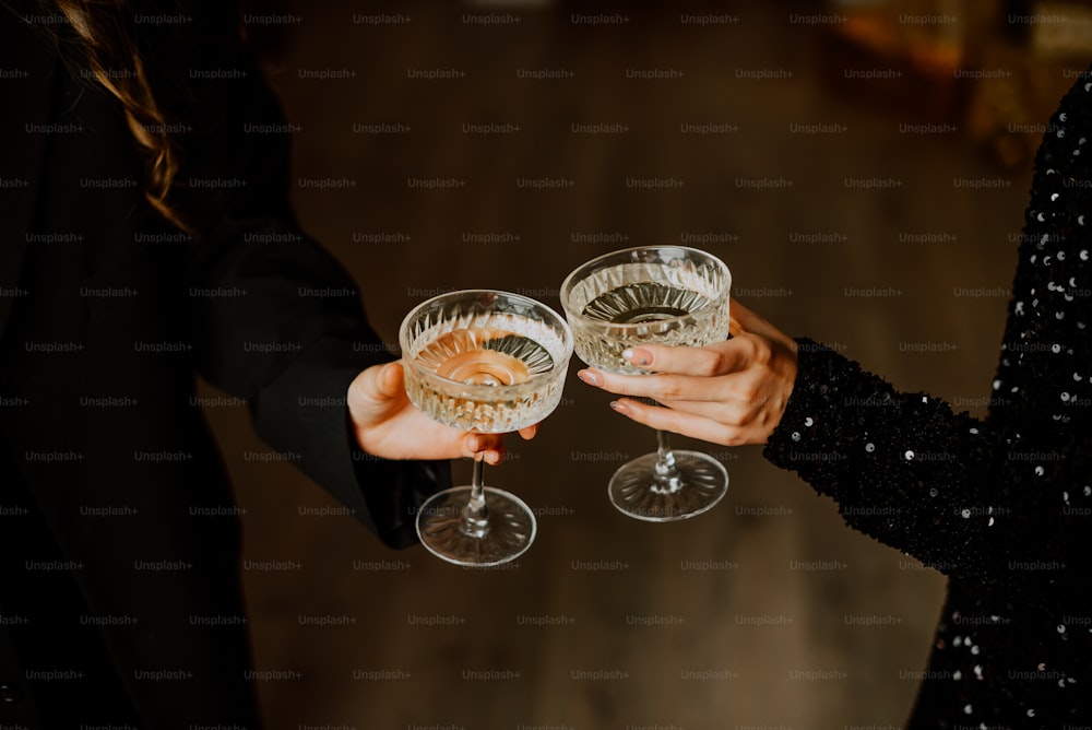 two people holding wine glasses in their hands