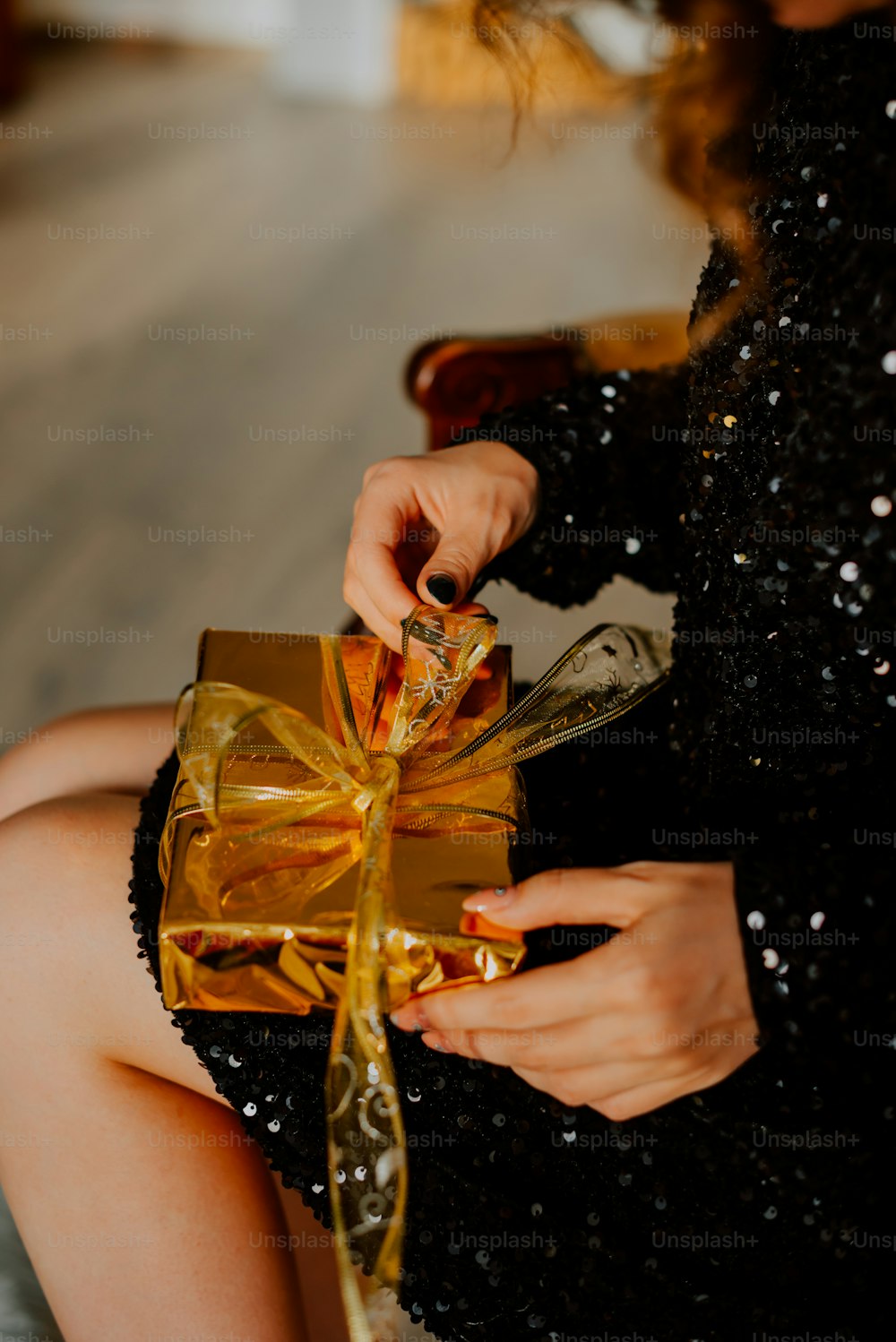 a woman in a black dress holding a gold gift box