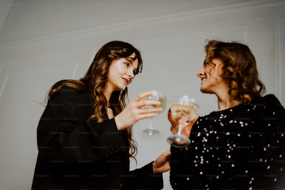 a couple of women standing next to each other holding wine glasses