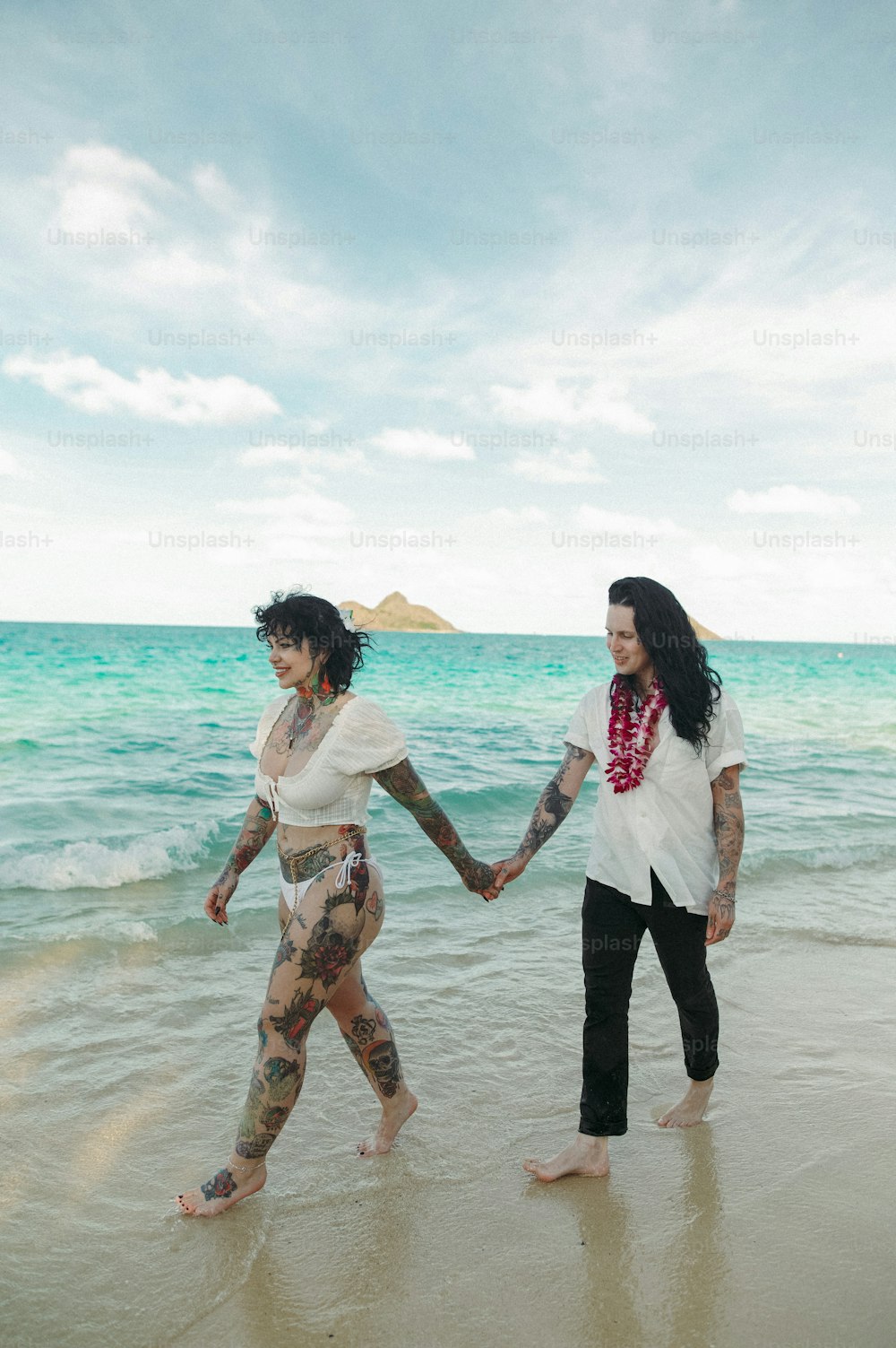 Dos mujeres caminando por la playa tomadas de la mano