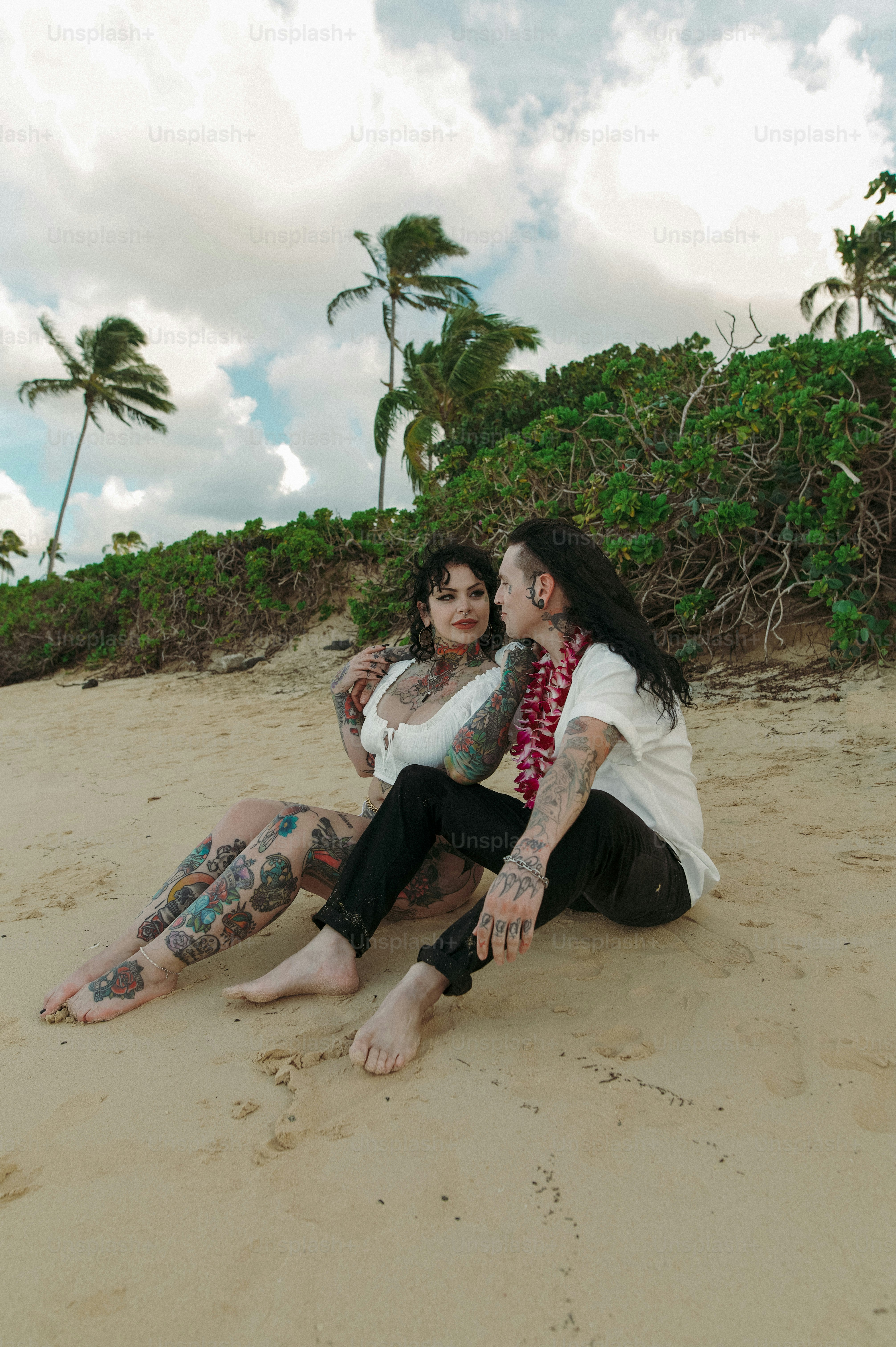 um casal de pessoas sentadas em cima de uma praia de areia