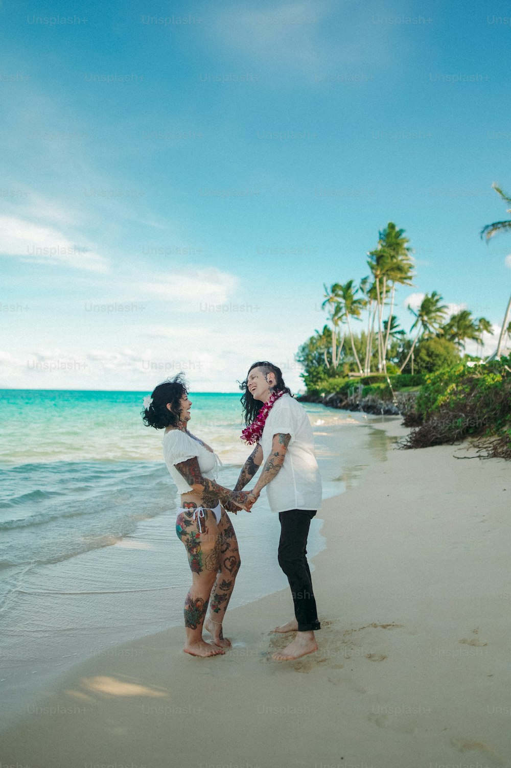 a man and woman standing on a beach next to the ocean