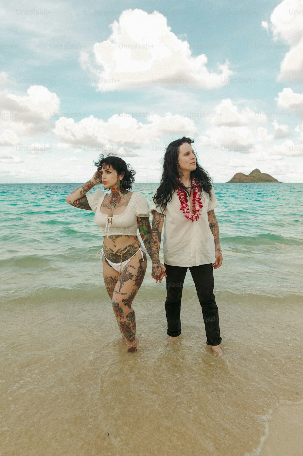 a couple of women standing on top of a sandy beach