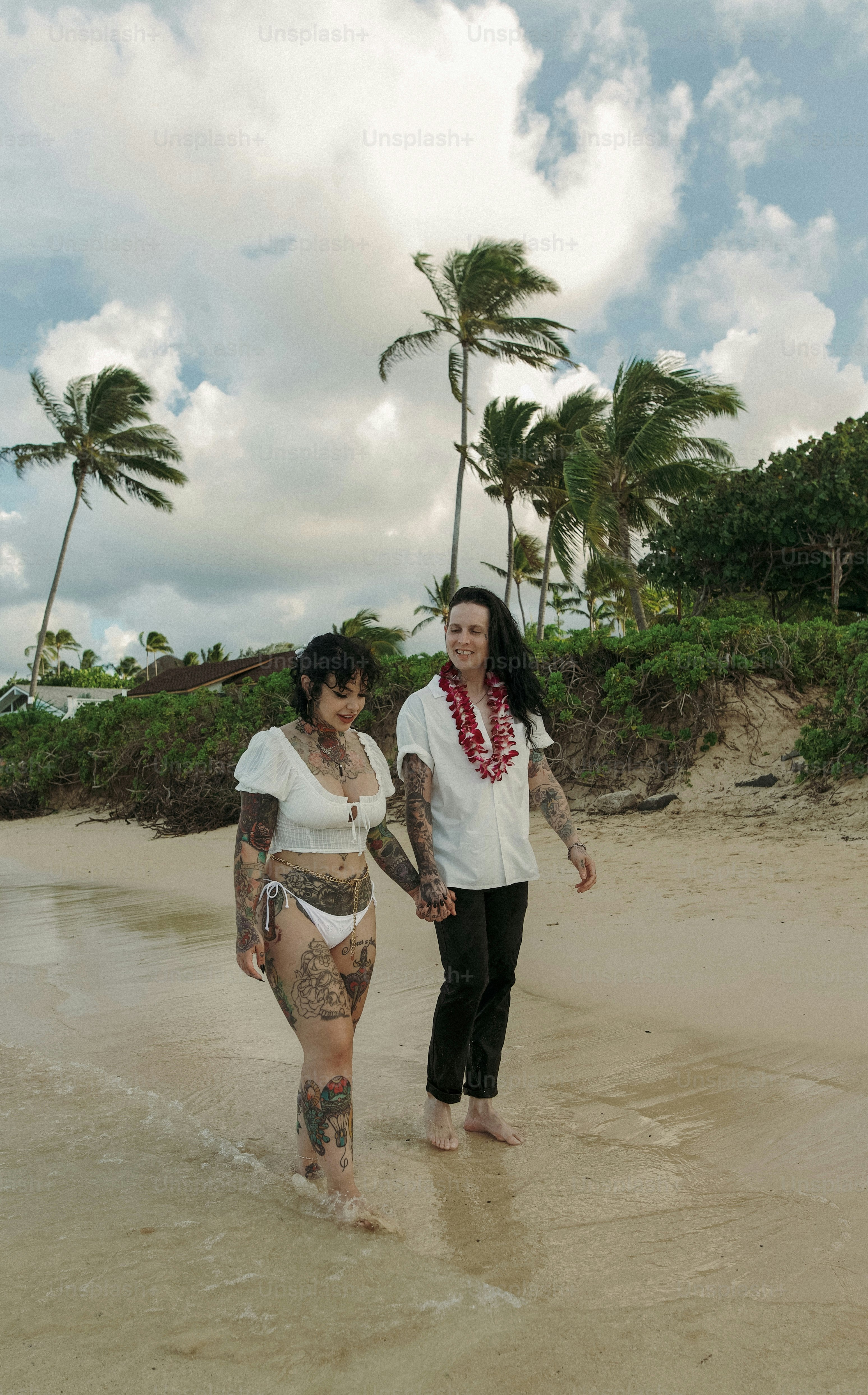 um casal de mulheres em pé em cima de uma praia de areia