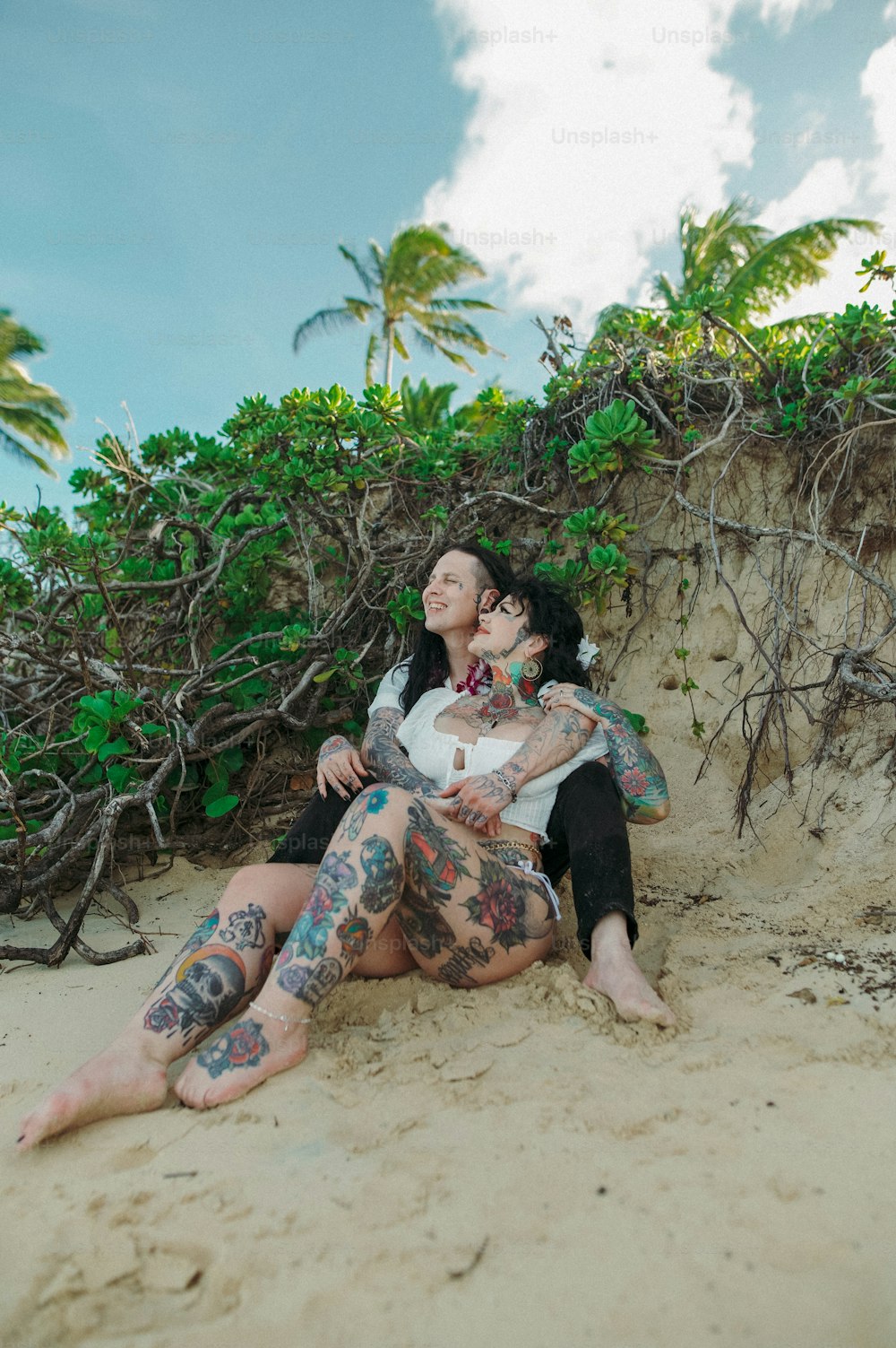 a man and a woman sitting on a sandy beach