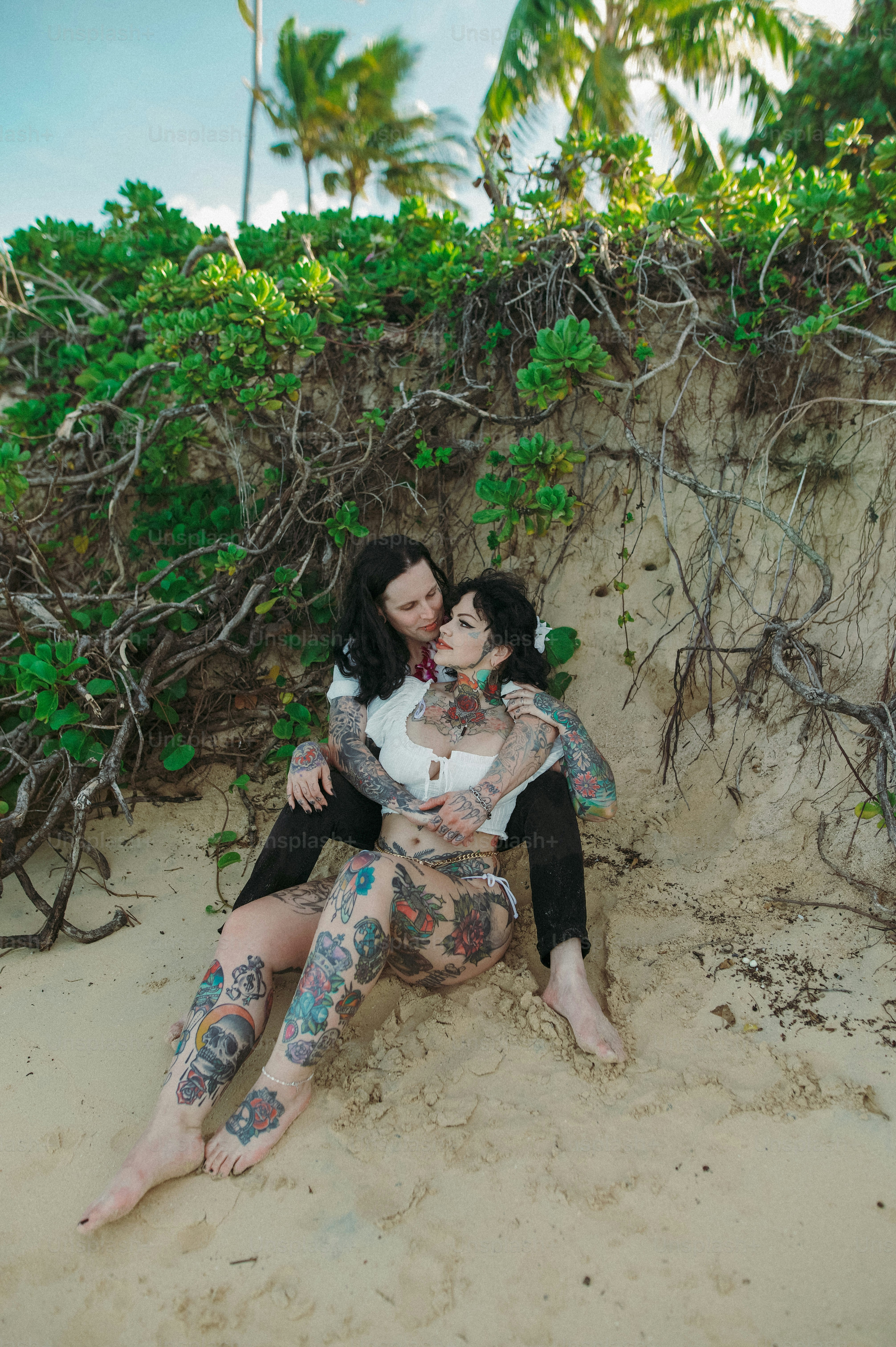 a couple of women sitting on top of a sandy beach